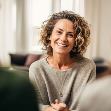 Smiling woman sitting in a therapy session, facing towards camera