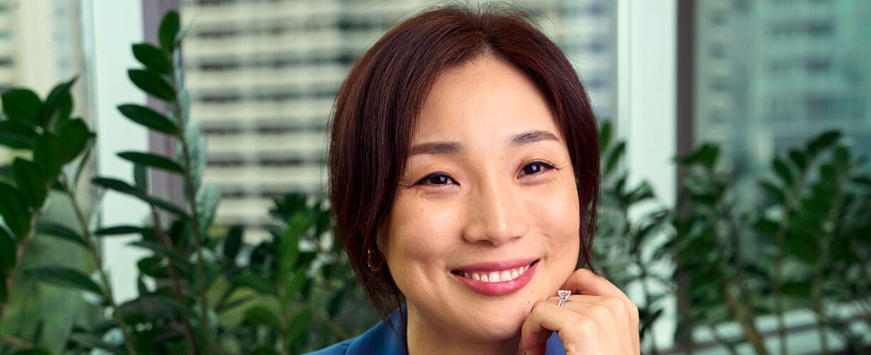 Stephanie Huang smiles at camera, with hand to face.