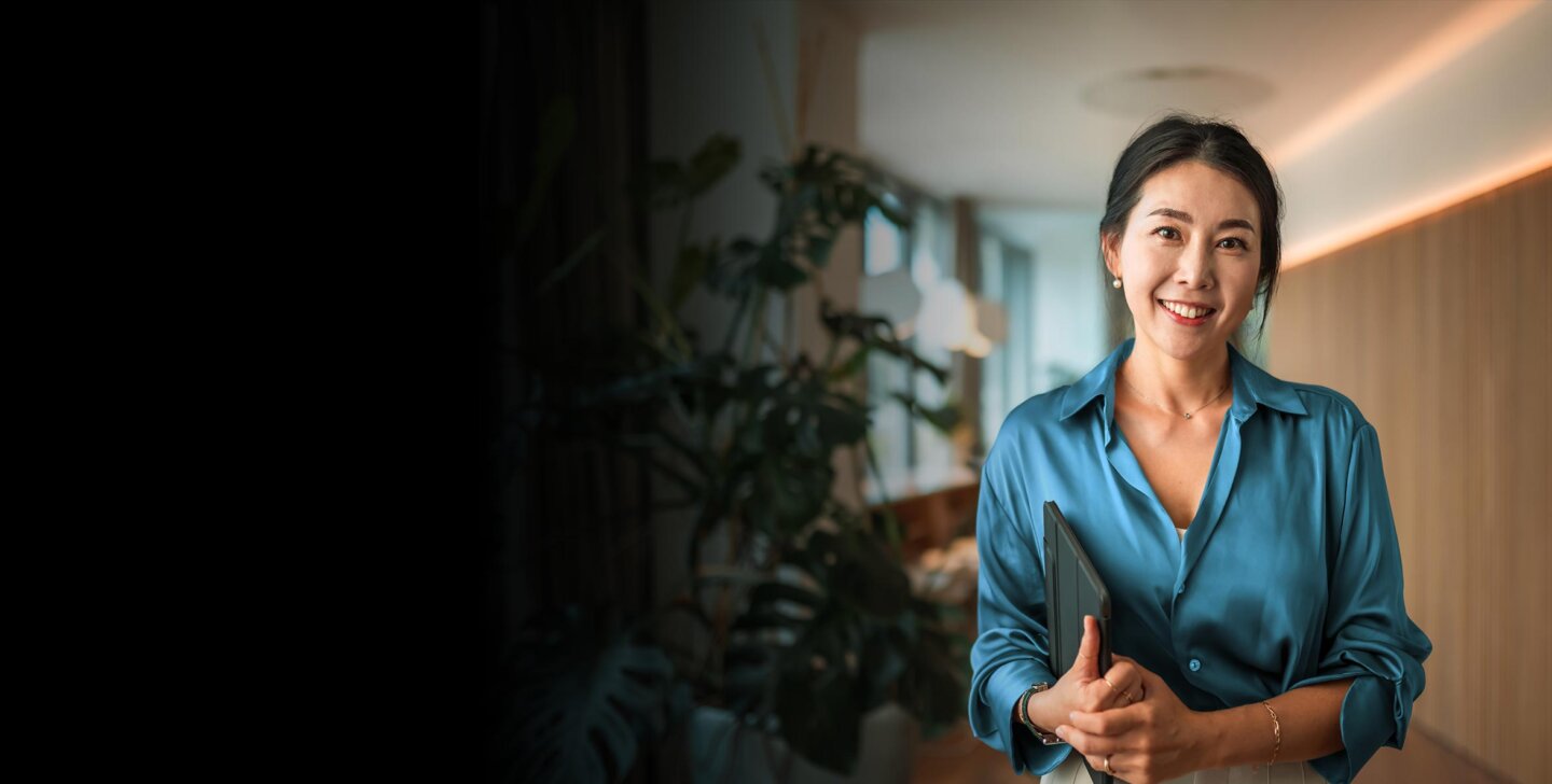 Smiling woman standing and looking towards the camera with a tablet under her arm