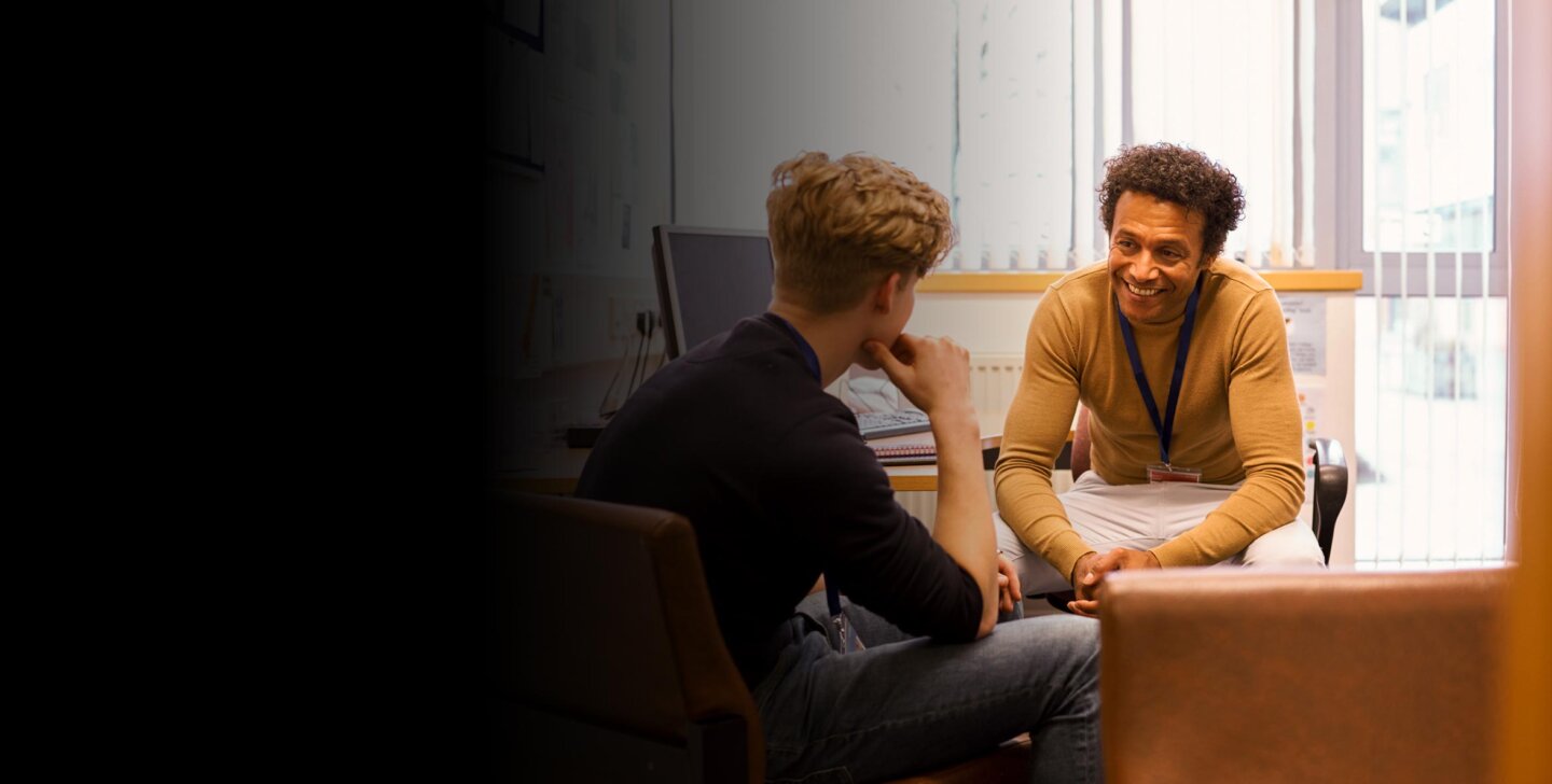 Smiling man sitting at a desk and chairs, meeting with a young client