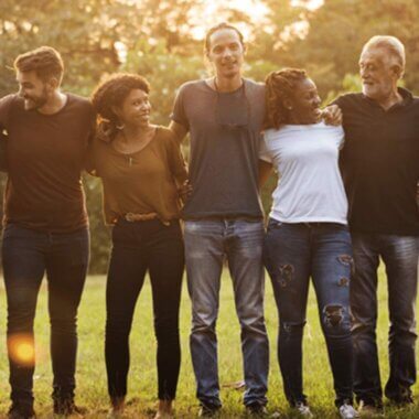 The ACAP Story A group of people stand in a park, arm in arm, at dawn.