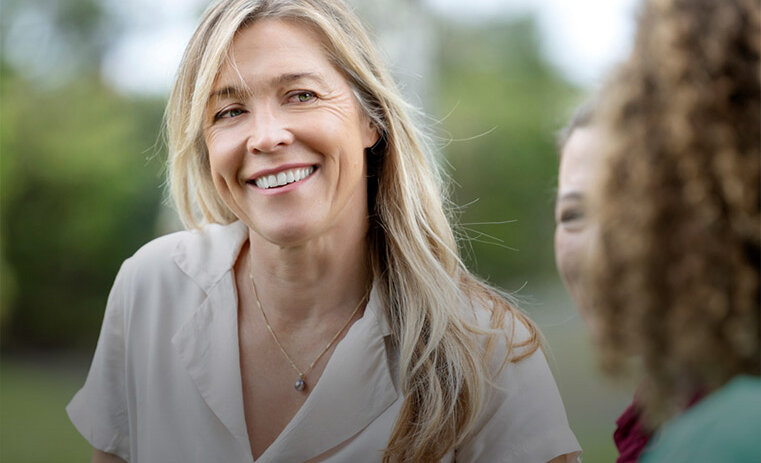A woman with blonde hair smiling towards camera and standing with two other women - ACAP Counselling (761x761)