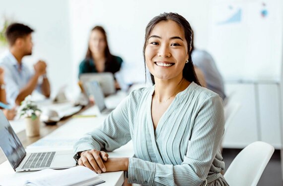 An ACAP law (PLT) student sitting at a desk in front of a laptop, with three other student sin the background (1140x752)