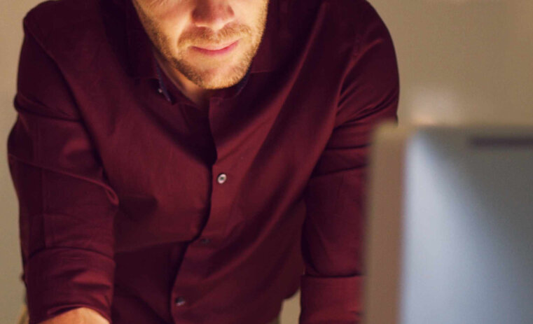 Bachelor of Psychological Science and Criminology campaign hero mobile A man standing with his arms on a desk, looking towards a laptop screen | Bachelor of Psychological Science and Criminology