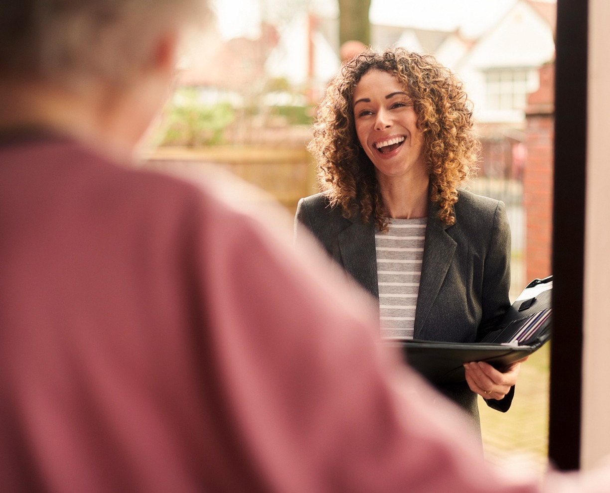 Social work - Adelaide scholarship A smiling female social worker standing at the doorway of a client with a folder in hand