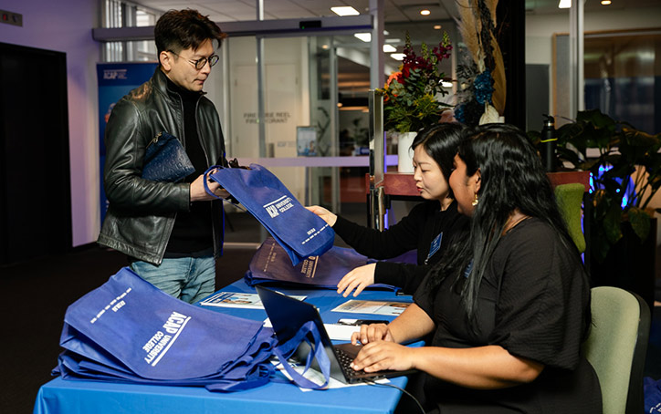 A prospective student receiving a merchandise bag from ACAP University College staff at an Info Night event (724x454)