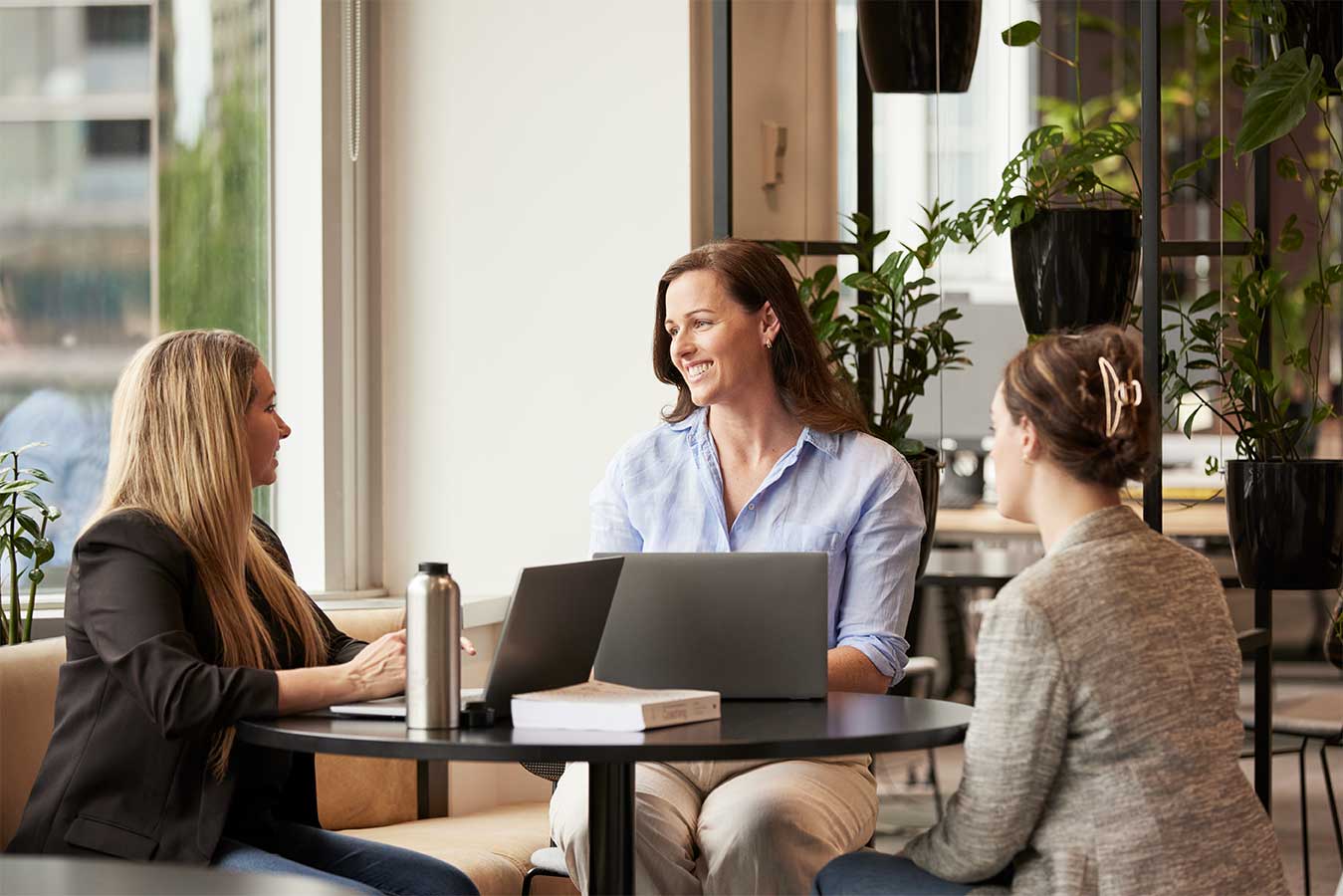 Woman speaking to two other women in corporate setting