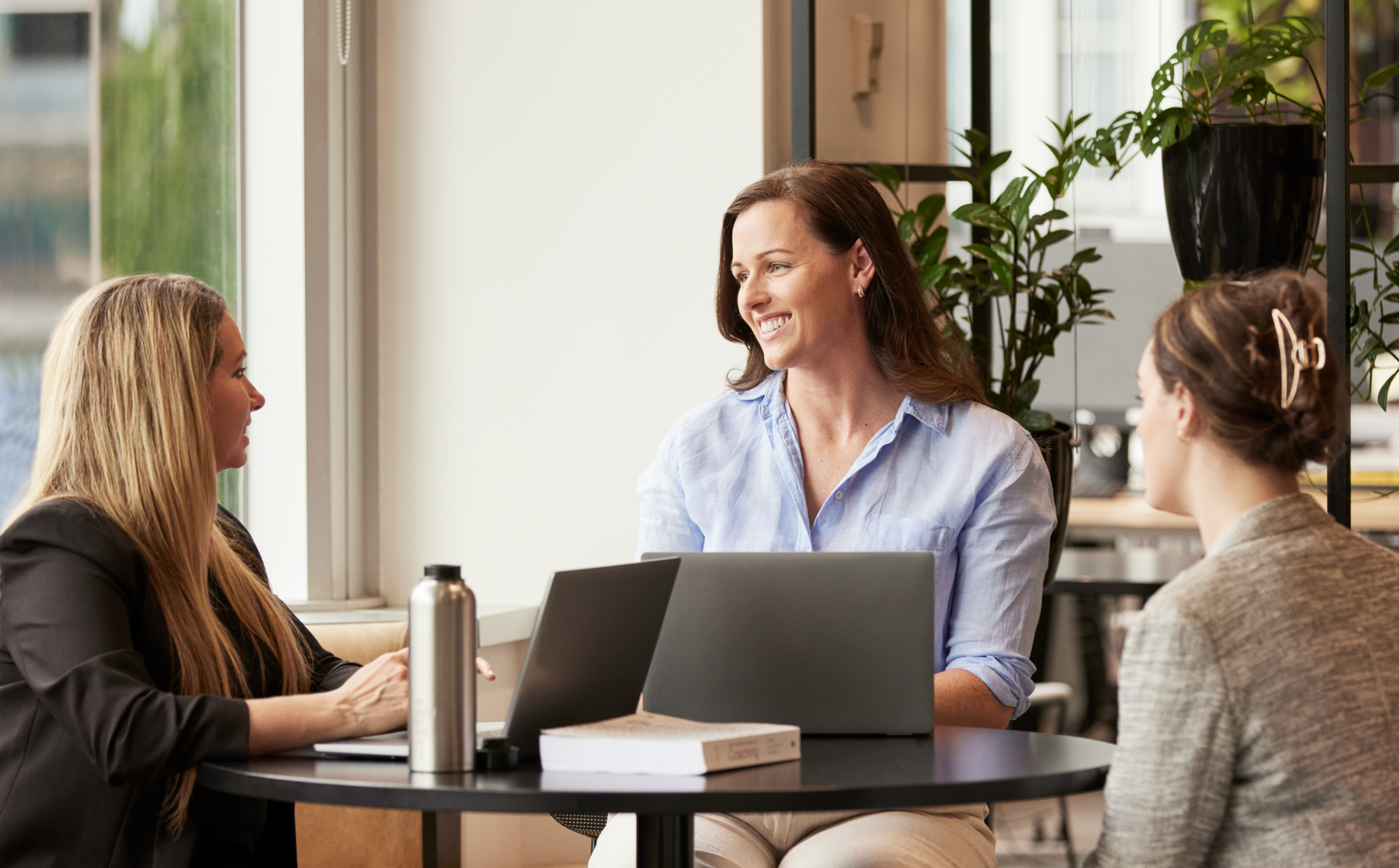 Sarah_Studying_resize Woman speaking to two other women in corporate setting