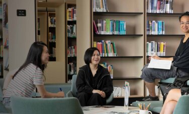 A group of students sitting in a group talking to each other at ACAP Sydney campus library - Calm & Conquer 2880x1188