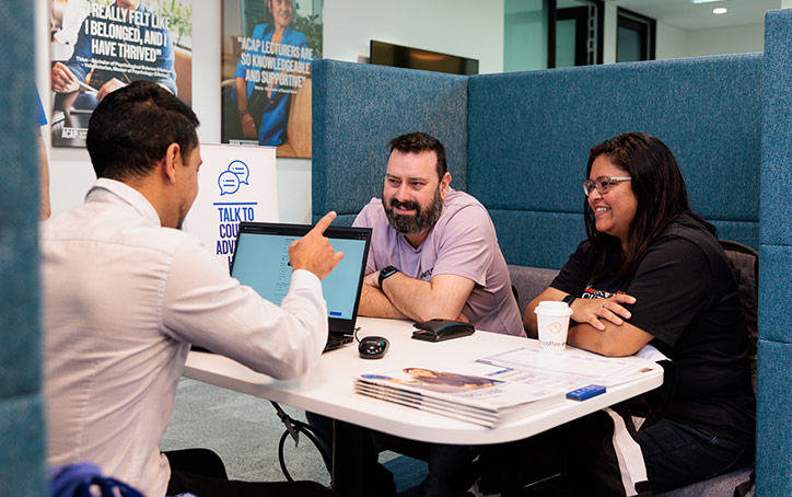 Two students sitting with a course advisor at an ACAP University College Open Day event (724x454)