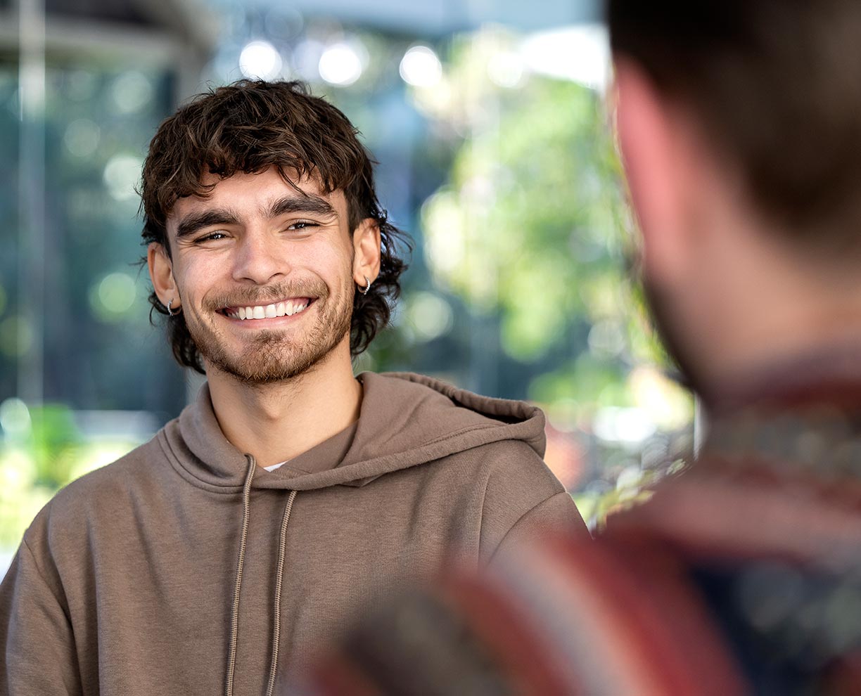 A young male student smiling toward the camera at a teacher in the foreground