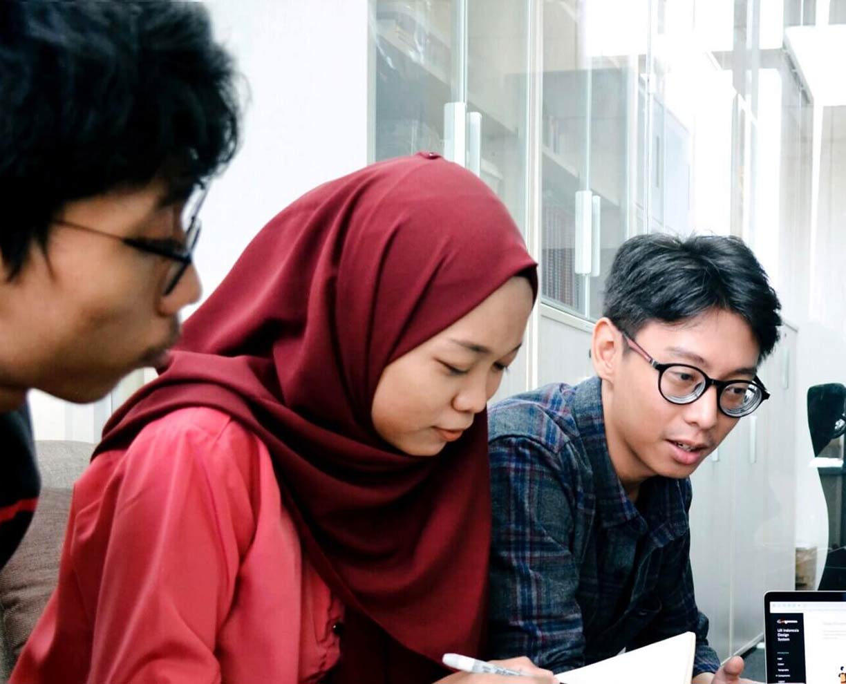 Three students working together at a desk in an office space (1224x990)