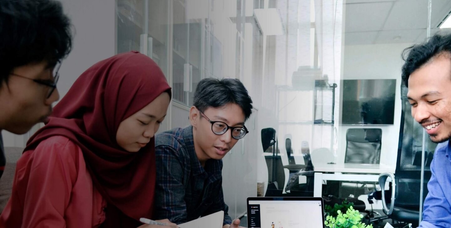 Four students sitting around a desk in a private study room, working on a research paper for an ACAP University College project (2880x1188).